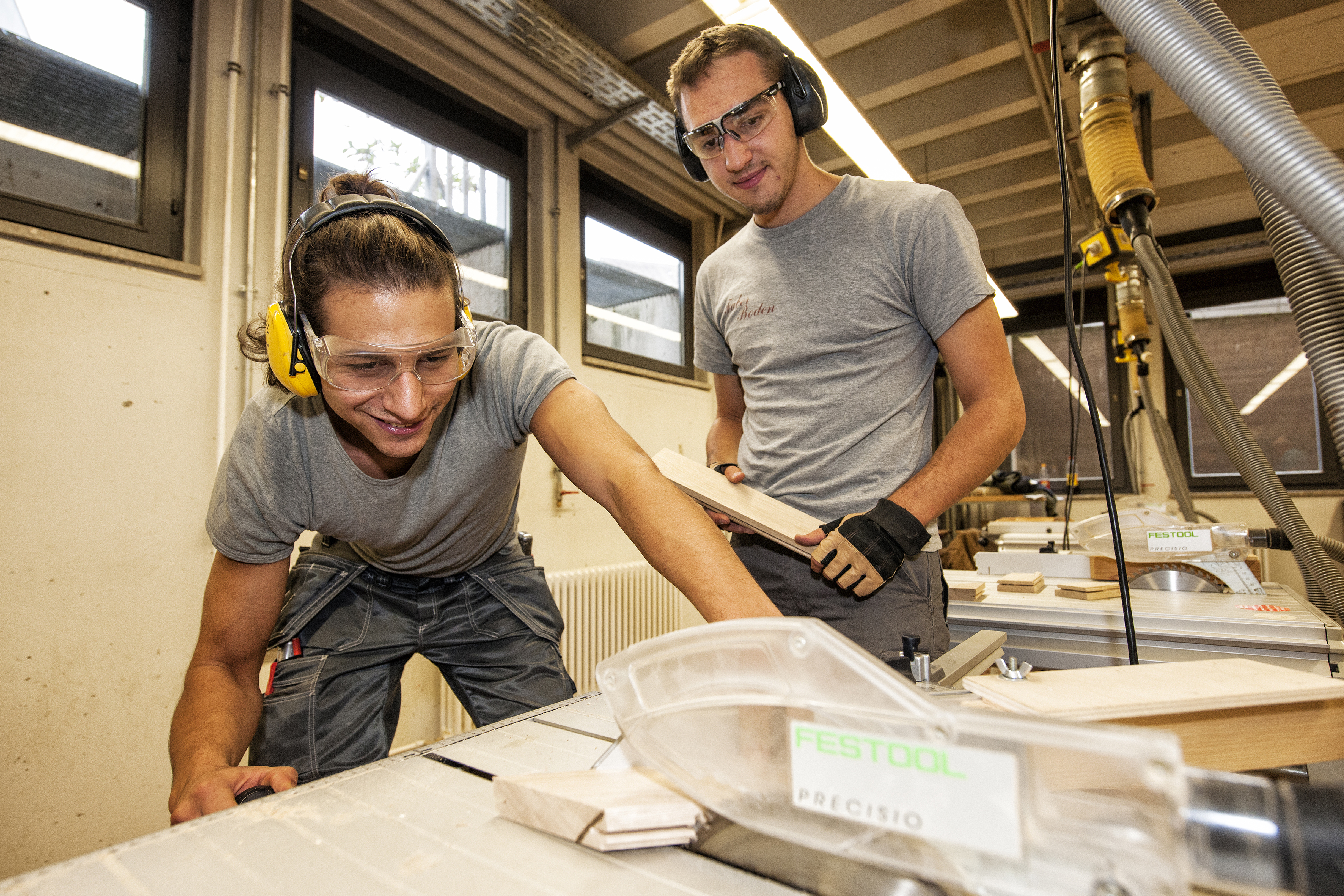 Zwei junge Männer bearbeiten in der Berufsschule Holz.