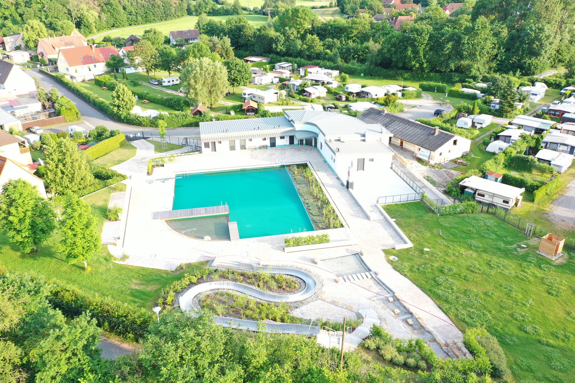 Luftaufnahme vom Naturbad in Münchsteinach mit dem türbisblauen Becken und viel grünflächen außenrum