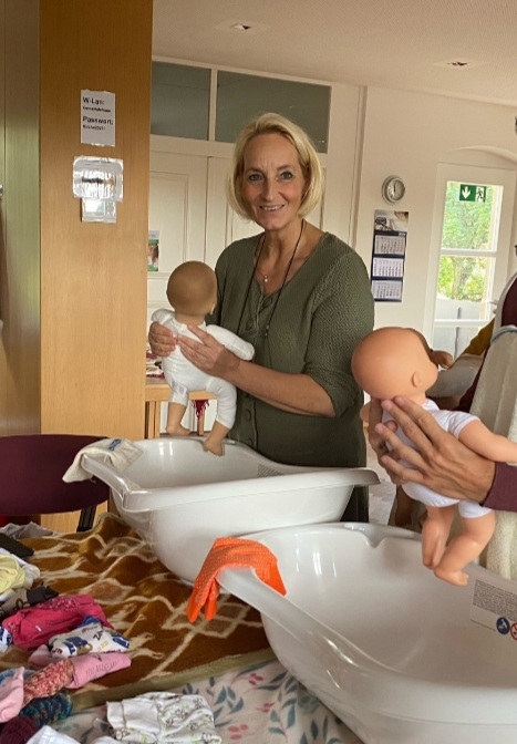 Frau badet eine Babypuppe