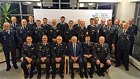 Gruppenfoto von Personen in dunklen Uniformen mit Abzeichen, die in zwei Reihen vor einem weißen Hintergrund mit dem Logo „Frankens MEHR Region“ stehen, aufgenommen in einem Innenraum mit großen Fenstern und einer grünen Pflanze links.