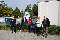 Sieben Personen stehen vor eine Windflag mit dem Logo der Familienstützpunkte