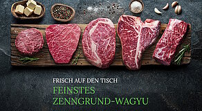 Verschiedene rohe Wagyu-Rindfleischstücke auf Holzbrett arrangiert – darunter Burgerpatty, Ribeye, T-Bone und stark marmoriertes Steak, umgeben von Butterwürfeln, Pfeffer, Salz, Knoblauch und Rosmarin, mit Text „FRISCH AUF DEN TISCH – FEINSTES ZENNGROUND-WAGYU“ vor dunklem Steinuntergrund.