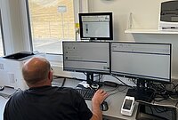 Mann sitzt vor mehreren Computerbildschirmen