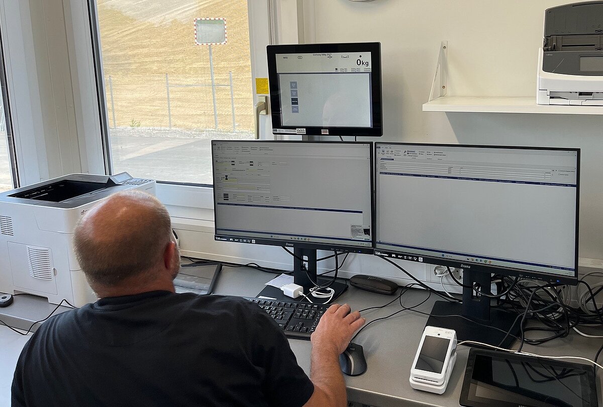 Mann sitzt vor mehreren Computerbildschirmen