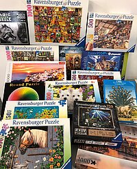 Verschiedene Ravensburger-Puzzle mit bunten Motiven und unterschiedlichen Teilezahlen in einer Verkaufspräsentation.