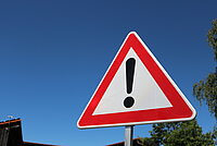Verkehrsschild Vorsicht mit Ausrufezeichen vor blauem Himmel