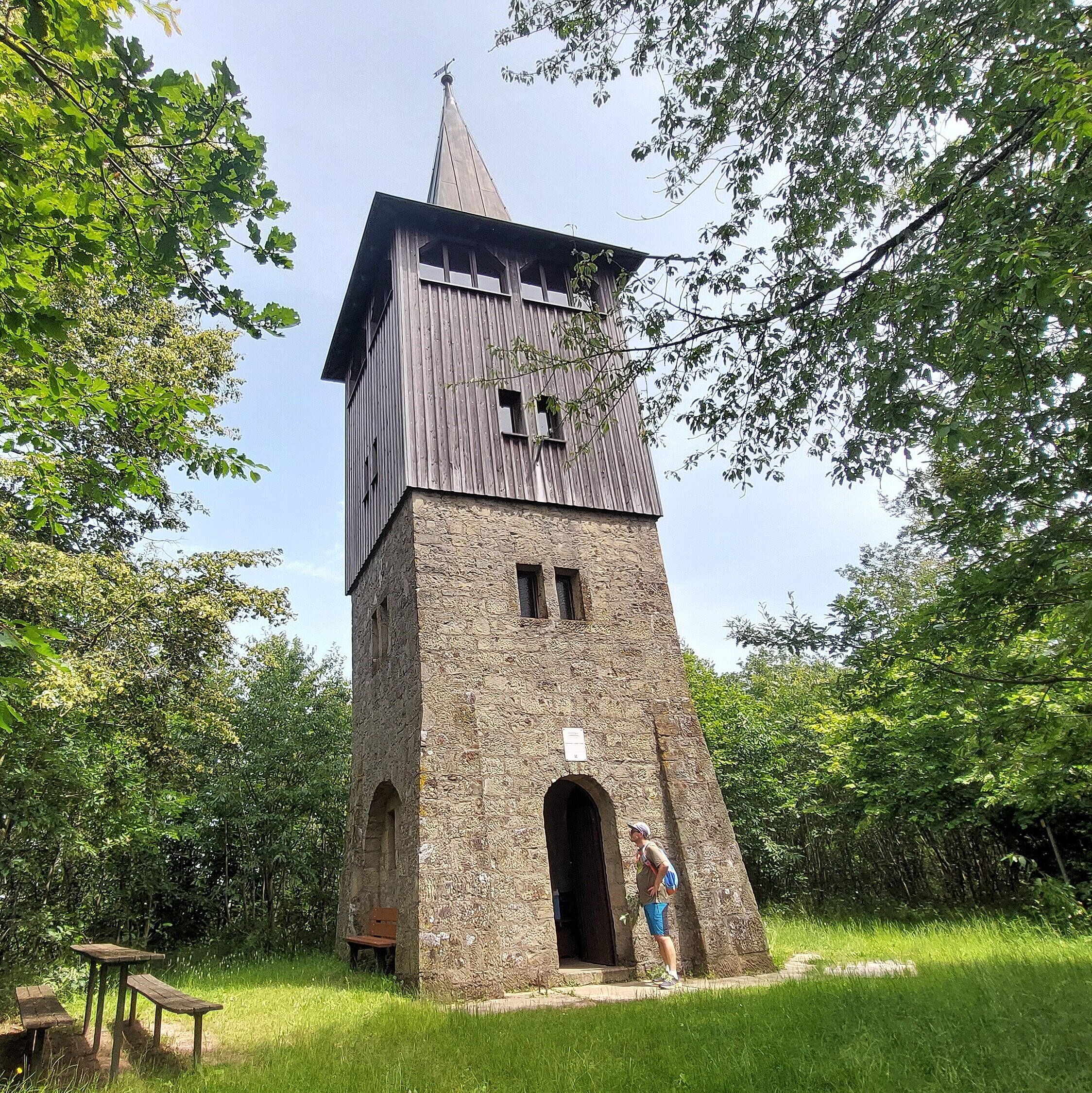 Andreas Därr Turm mit spitzen Dach auf einem kleinen Platz mit Wanderschildern Richtung Weigenheim