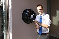 Landrat Dr. Christian von Dobschütz präsentiert den  neuen Defibrillator am Haupteingang des Landratsamtes.