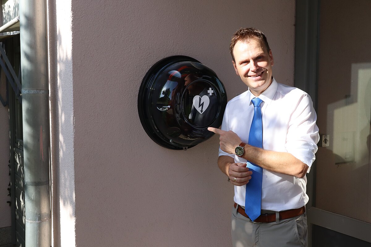 Landrat Dr. Christian von Dobschütz präsentiert den  neuen Defibrillator am Haupteingang des Landratsamtes.