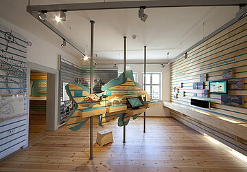 Ausstellungsraum im Karpfenmuseum mit einem großen Holzkarpfen in der Mitte in warmen Farben