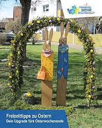 Osterdeko vor einem Osterbogen mit Osterhasen davor