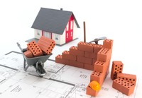 Modell-Einfamilienhaus mit kleinen Bausteinen und Bauplan.