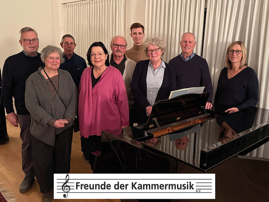 Bild der Vorstandschaft vor einem Flügel mit dem Logo einer Musikzeile