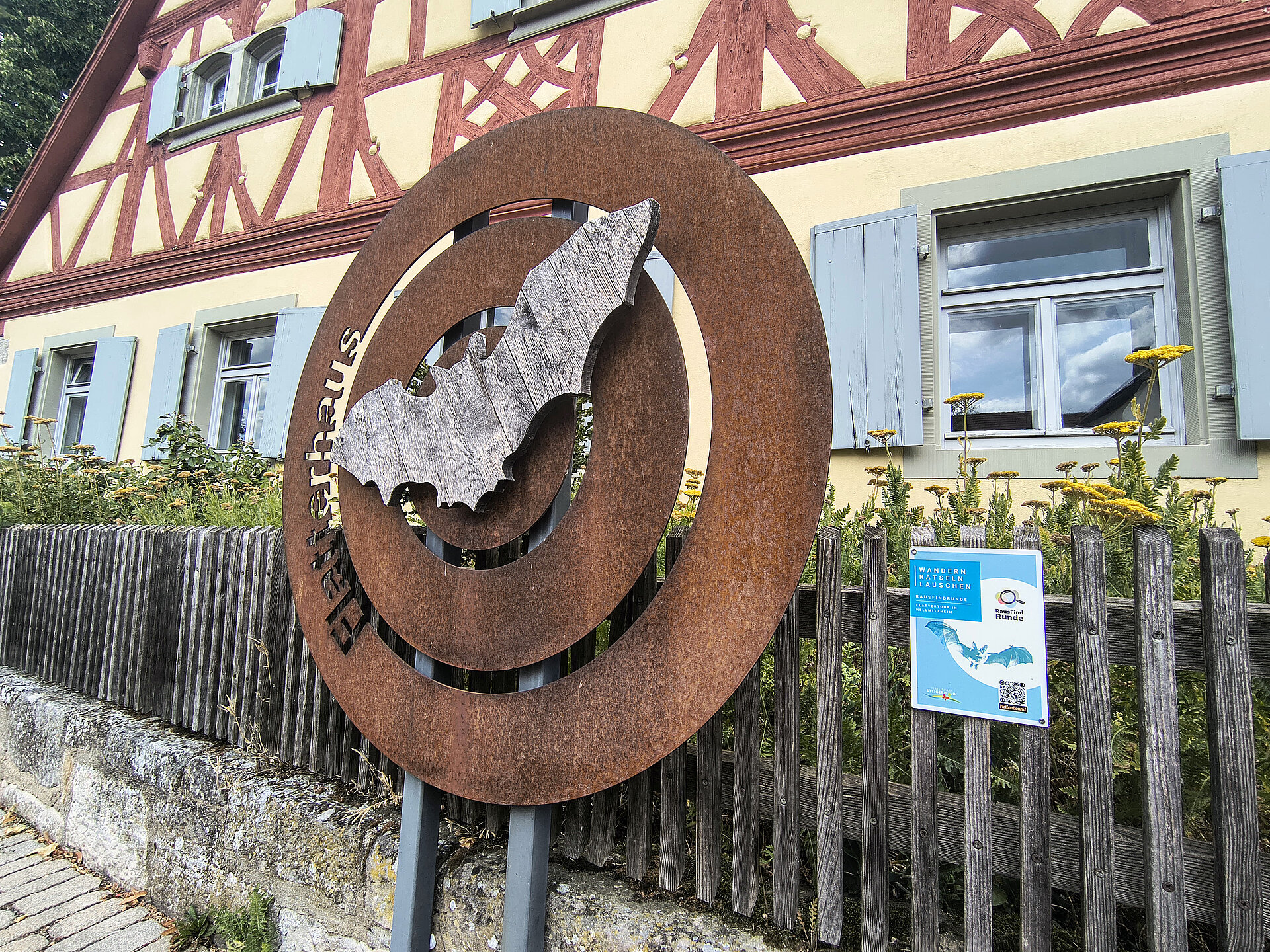 Eine Fledermausskulptur vor einem Fachwerkhaus als Hinweisschild auf die RausfindRunde
