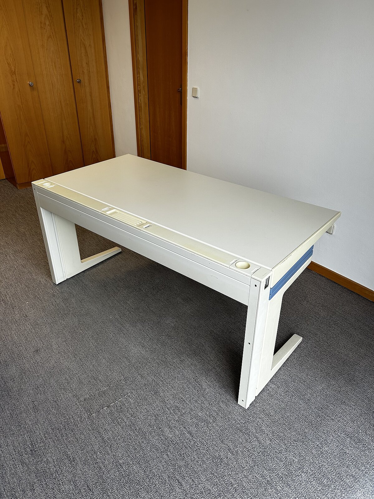 Moderner weißer Schreibtisch auf grauem Teppich vor Holzvertäfelung – schlichtes Büro- oder Arbeitsmöbel.