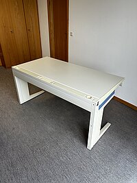 Moderner weißer Schreibtisch auf grauem Teppich vor Holzvertäfelung – schlichtes Büro- oder Arbeitsmöbel.