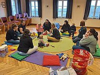Mütter mit Kindern sitzen am Boden im Kreis