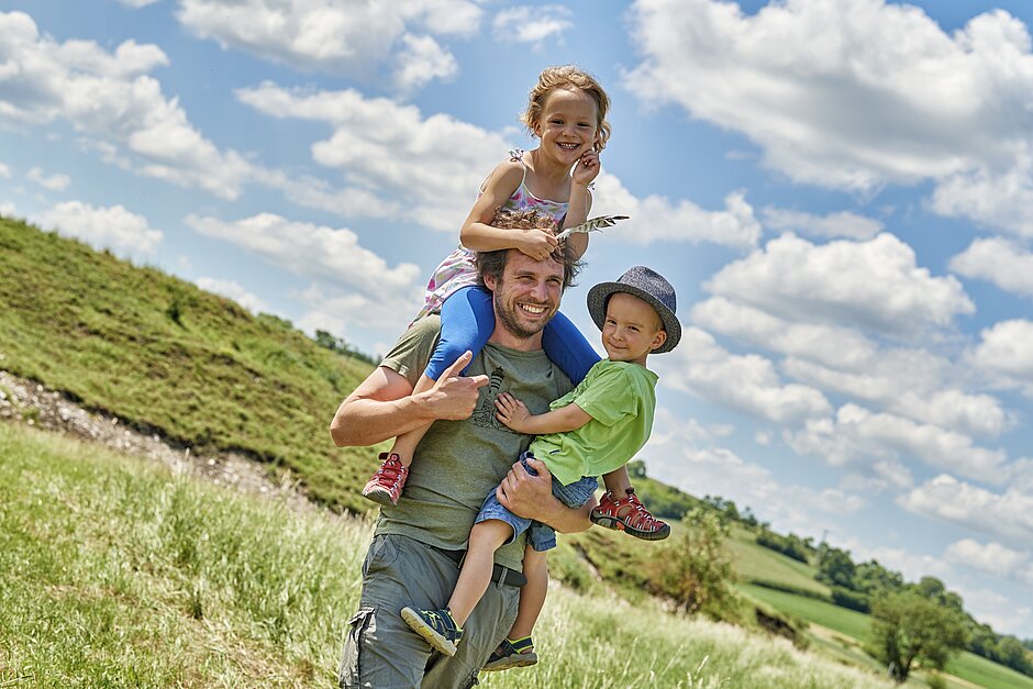 Vater mit zwei kleinen Kinder bei einem Spaziergang in der Natur