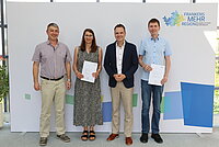 Vier Personen vor der Fotowand mit dem Logo "Frankens Mehrregion"
