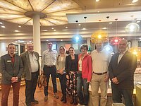 Gruppe von acht Personen steht in einem Raum