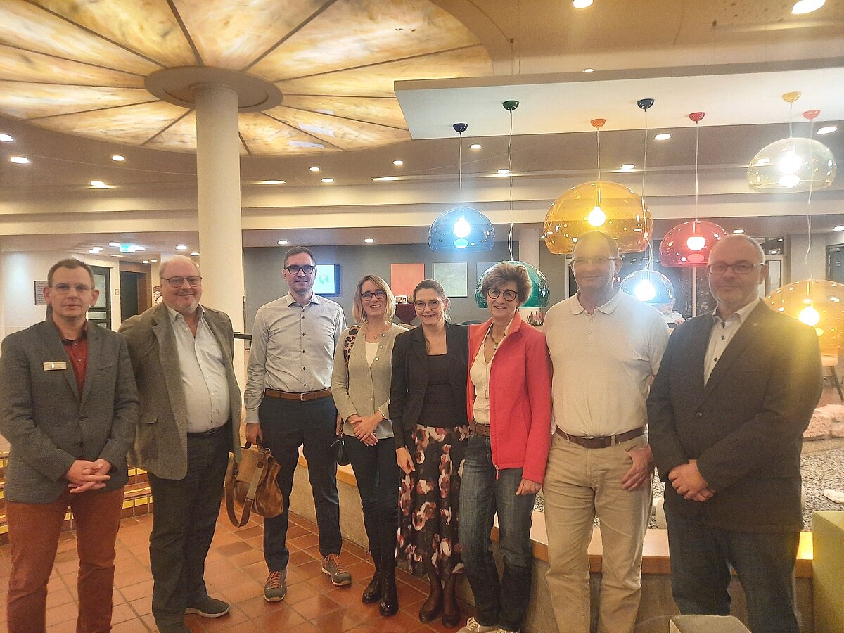 Gruppe von acht Personen steht in einem Raum