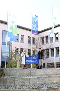 Die beiden Mitarbeiterinnen des Frauennotrufs, Iris Regner und Sanja Knezevic, hissen anlässlich des Gedenktags die Fahne am Landratsamtgebäude.