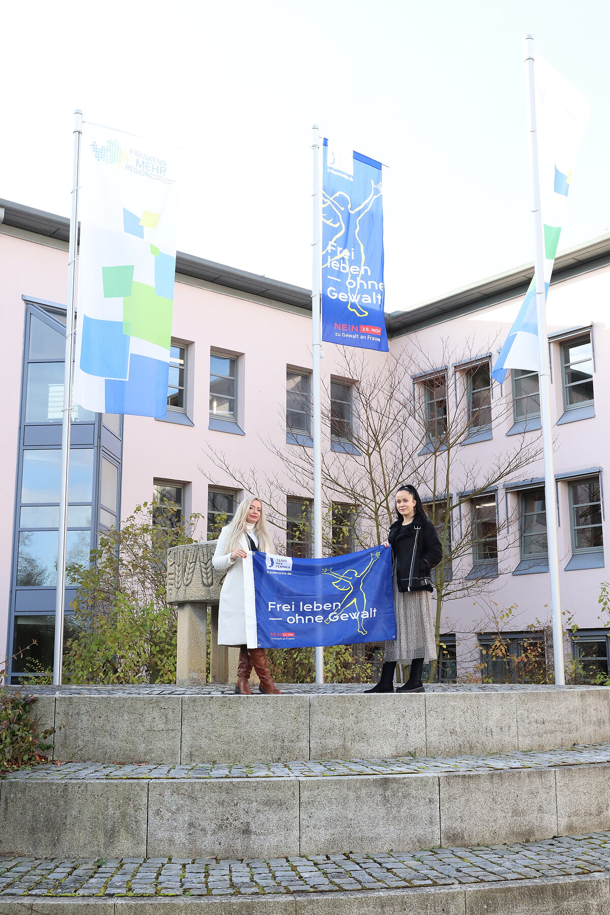 Die beiden Mitarbeiterinnen des Frauennotrufs, Iris Regner und Sanja Knezevic, hissen anlässlich des Gedenktags die Fahne am Landratsamtgebäude.