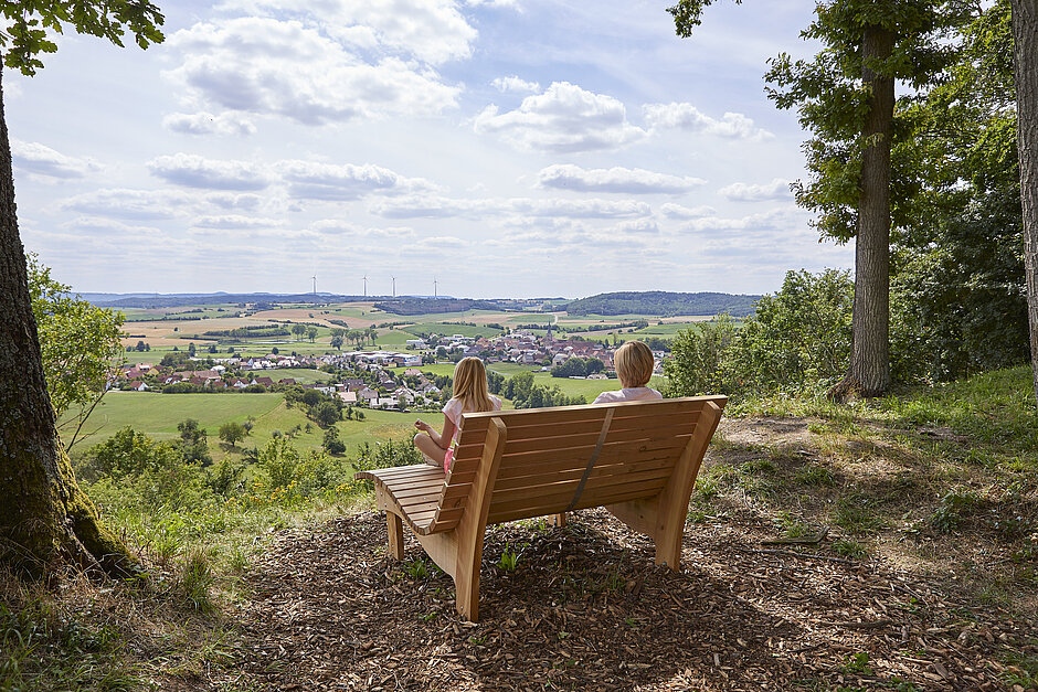 Ausblick in die Natur von einem Berg hinter einer Bank die zum Tal gewendet is