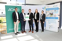 Fünf Personen stehen vor Roll-Ups, eines von der AOK, eines von der Gesundheitsregionplus, eine Person hält den Gesundheitsbericht in der Hand.