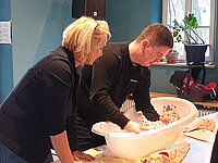 Eine Frau und ein Mann baden eine Babypuppe