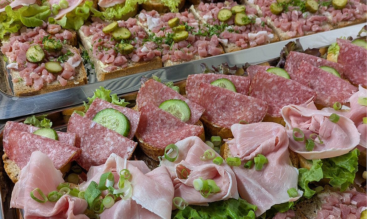 Ein appetitvolles Buffet mit belegten Broten in bunter Vielfalt: Salami, Schinken, Gurke, Kräuter und feine Fleischzubereitungen – liebevoll angerichtet und bereit für den Genuss. Ein Klassiker für jeden Anlass, der mit Geschmack und Frische überzeugt.
