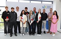 Elf Personen stehen vor einem weißen Hintergrund mit dem Logo „Frankens MEHR Region“ und halten jeweils eine rot-weiße Schultüte, rechts eine Person in einem pinken Kleid.