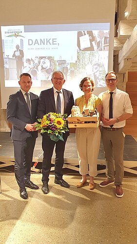 4 Personen vor einer Leinwand mit Geschenken in der Hand