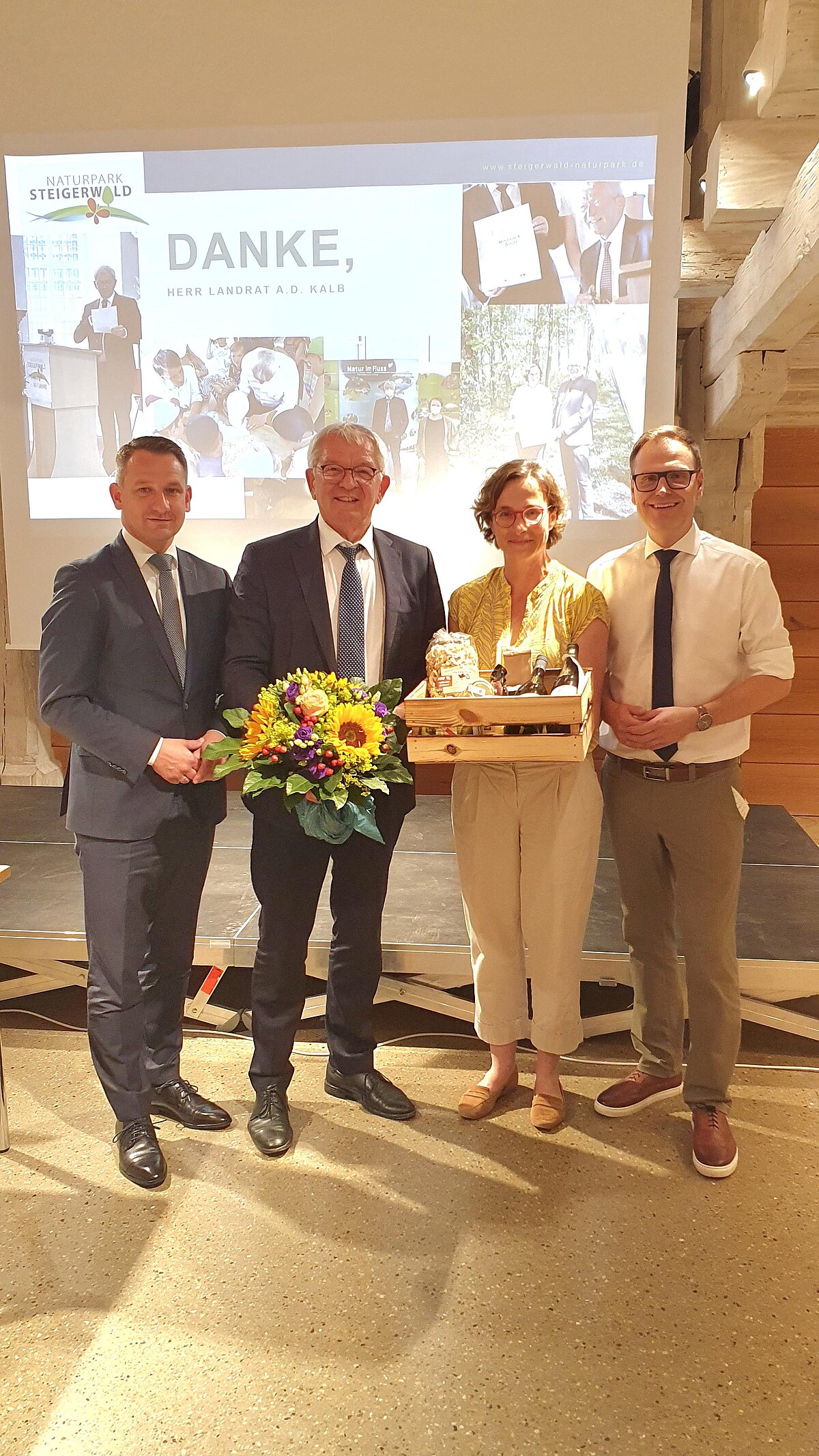 4 Personen vor einer Leinwand mit Geschenken in der Hand