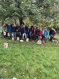 Rund 30 Personen stehen vor einem Apfelbaum auf einer Streuobstwiese