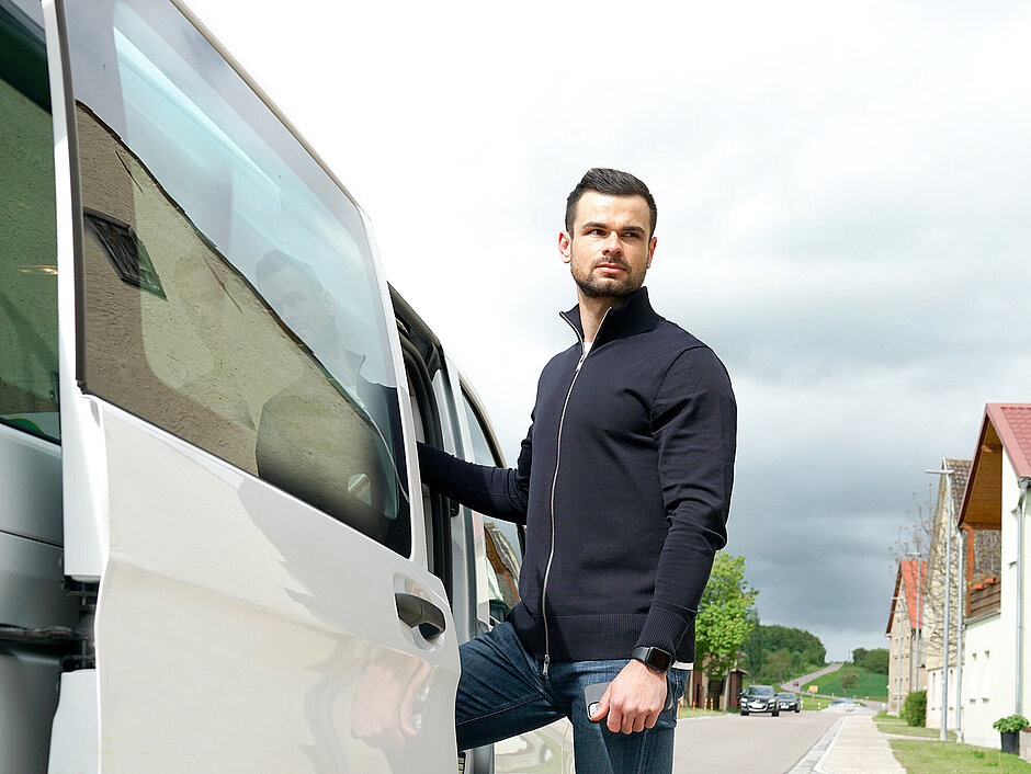 Ein junger Mann der in der tür eines 9 Sitzer Busses steht