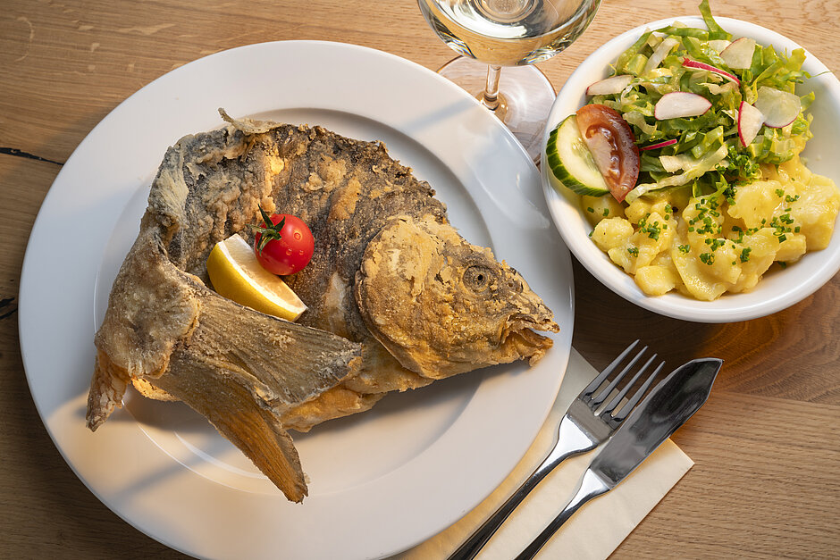 Halber gebackener Karpfen auf Teller mit Kartoffelsalat