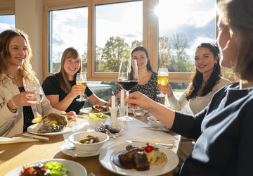 5 junge Frauen beim Essen im sonnigen Gastraum der Steinachstube in Münchsteinach